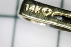 Closeup of the Hallmark of the Preowned Stuller Pear Shaped Peridot Diamond 14k Gold Pendant with 14K and a diamond icon etched